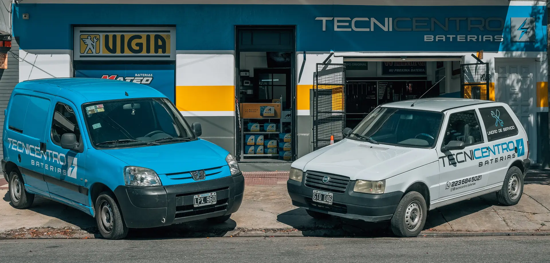 Unidad de servicio de Tecnicentro Baterías junto a un auto con el capó abierto
